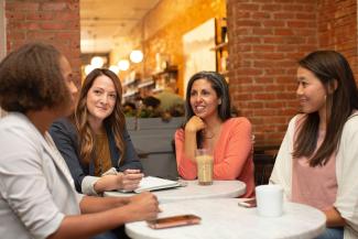 woman in black jacket sitting beside woman in white blazer by LinkedIn Sales Solutions courtesy of Unsplash.