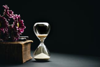 clear hour glass beside pink flowers by Nathan Dumlao courtesy of Unsplash.