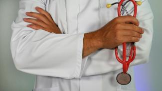 doctor holding red stethoscope by Online Marketing courtesy of Unsplash.